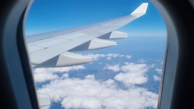 Stunning aerial view from an airplane illuminator showing the wing flying over a beautiful blue sky with scattered white clouds