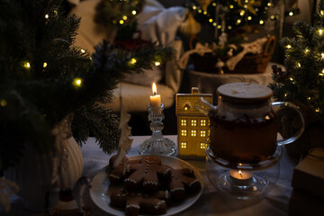 There are gingerbread men on the plate. A decorated Christmas tree and festive ornaments are in the background.
