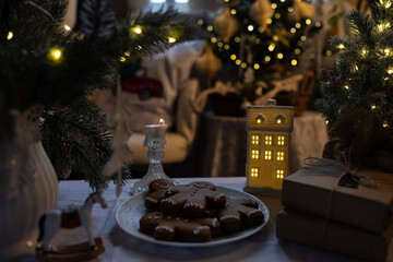 There are gingerbread men on the plate. A decorated Christmas tree and festive ornaments are in the background.