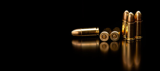 Several shiny brass pistol cartridges on a reflective black background