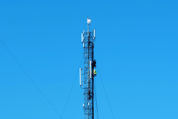 Maintenance staff at the work. High-altitude work. Workers repair cell tower