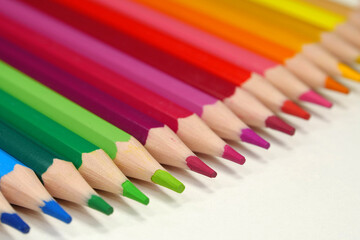 New wooden colored pencils of rainbow colors, perfectly sharpened, lie on table
