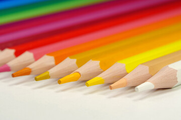 New wooden colored pencils of rainbow colors, perfectly sharpened, lie on table
