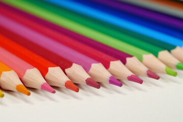 New wooden colored pencils of rainbow colors, perfectly sharpened, lie on table