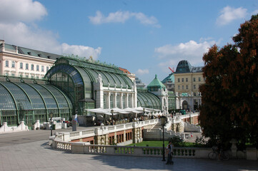 A view of the Palmenhaus in Vienna, Austria, with people walking and dining outside.