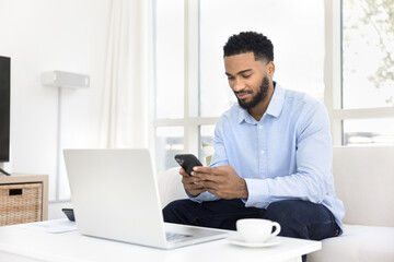 Focused man using smartphone seated on sofa