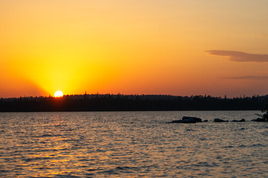 Sun dropping behind the tree line Granite Hill Lake Ontario Canada
