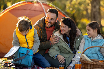 Family enjoys picnic in sunny park in autumn