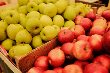 Fresh green and red apples stacked in wooden crates at a local market. Healthy organic fruit for diet and natural living