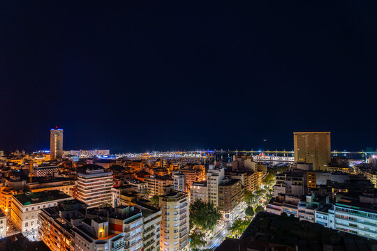 Cityscape at night with illuminated buildings and starry sky.