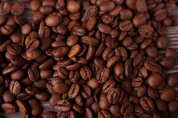 close-up view of rich, aromatic roasted coffee beans spread on a wooden surface, showcasing their dark brown color and textured surface, evoking a sense of warmth and comfort, harvested, inviting