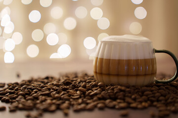 aesthetic close-up of a creamy coffee cup surrounded by dark roasted beans with soft bokeh light background creating a cozy and inviting atmosphere, ambient, stylish, decorative, elegant