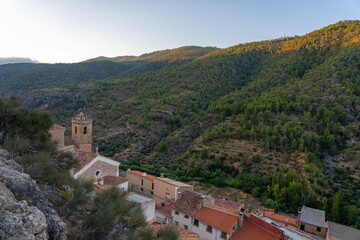 Obraz premium Village nestled in a green, sunlit mountain valley.