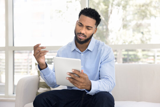 African man feels frustrated or confused while looks at tablet