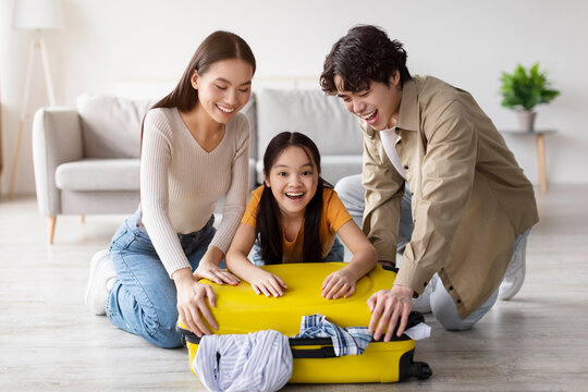 A family joyfully prepares for a trip, packing a vibrant yellow suitcase in their cozy living room. Laughter fills the air as they share the packing task together.