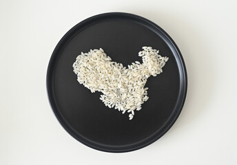 Uncooked white rice grains arranged into a map of China, presented on a minimalist black plate