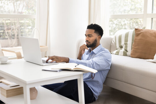 African man working on his laptop looks pensive and thoughtful
