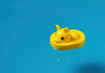 A cheerful classic yellow bath toy floating peacefully on blue water, symbolizing cleanliness, nostalgia, and simple childlike play, health, nostalgic, surface