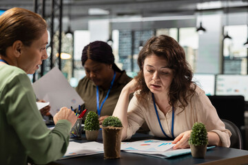 Focused team of managers reviewing data insights on papers, collaborating in a modern boardroom session. Discussing progress indicators and setting the foundation for a corporate success story.