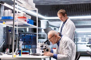 Experienced researchers using microscope optics in a lab research study. Sliding the sample tray...