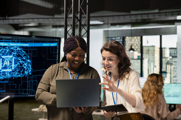 Powerful team of diverse associates review AI generated analytics from TV monitor, applying machine...