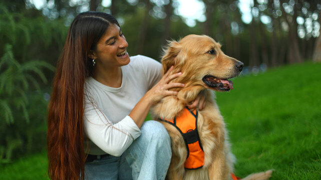 Woman petting golden retriever dog in park enjoying companionship - Powered by Adobe