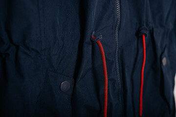 Dark blue jacket with red drawstrings, close-up of fashion detail and fabric texture.