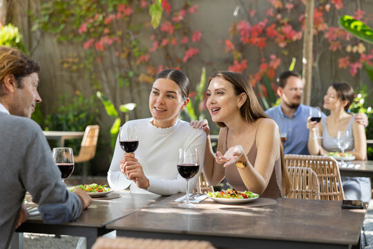 Fototapeta Two positive women are having lunch with a man - chatting and sharing news