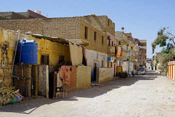 Narrow, dirty dirt road between crumbling multi-story buildings