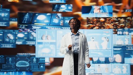 Smiling doctor in lab coat pleased by medical research data while monitoring interactive dashboards. Happy clinician satisfied with medical reports on multimedia wall, camera A
