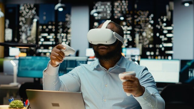 Black male worker using VR glasses and gadgets to draft a project plan, forecasting projections and documenting risk assessment results. Organizing tasks for business goals.