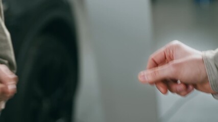 Cropped of sales person gives customer a key from a brand new car. The atmosphere is vibrant, showcasing a variety of vehicles and features.