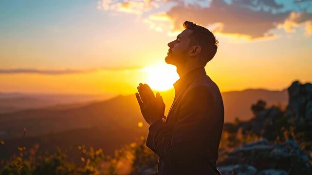 Man praying at sunset on a mountain top.
