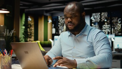African american person writing a yellow memo sticker as a reminder, trying to finish a task at the office after hours. Male employee placing a sticky note label as a memo, stationery.