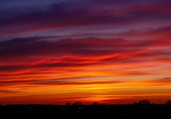 Majestic twilight sky bursting with deep orange, fiery red, and violet hues. Streaks of cirrus clouds drift peacefully as daylight fades ,peaceful ,vastness ,orange
