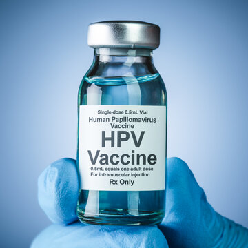 Nurses hand in blue medical gloves holding a vaccine bottle with HPV text. Health care concept of prevention or treatment of human papillomavirus and cancers caused by the virus.
