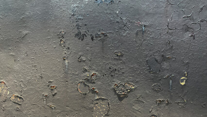 close up of old black paint on metal surface showing peeling, cracking, and rust spots — an example of low quality paint or improper surface preparation before coating