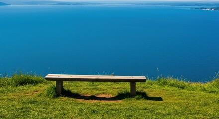 A rustic wooden bench provides a peaceful spot on a lush green hilltop, offering a tranquil scenic view overlooking a vast blue lake below ,empty ,bench ,blue sky