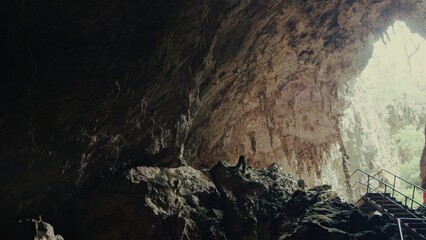 Exploring a natural cave with rock formations and bright light streaming in at midday