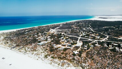 Beautiful coastal landscape showcasing a serene beach and vibrant blue ocean near a small town on a sunny day