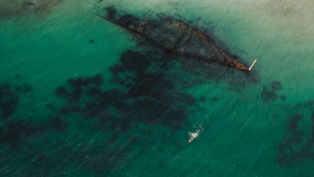 Exploring a shipwreck in clear turquoise waters near a rocky shoreline at sunset