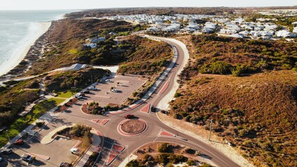 Scenic view of coastal roundabout with parking area near the beach during sunny daytime