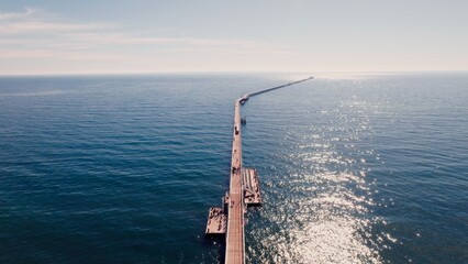Scenic view of a long pier reaching into calm ocean waters under a clear blue sky