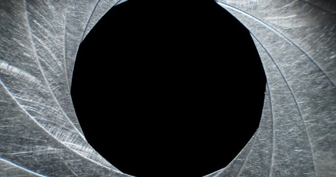 Circular blades of a mechanical iris create a precision opening controlling amount of light entering a camera lens with the opening mechanism controlling the aperture and the depth of field in focus.