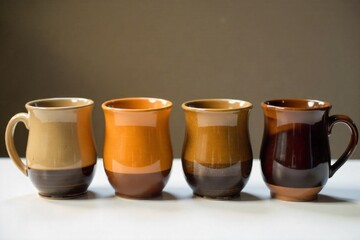Kiln Fired Ceramic Mugs A still life arrangement of four handcrafted ceramic mugs with different, intriguing glazes. They are positioned on a simple, clean surface, bathed in soft, directional light