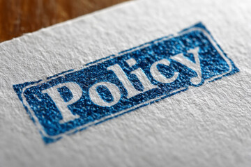 Macro shot of the word &ldquo;Policy&rdquo; printed in blue ink on textured white paper, symbolizing governance, compliance, and legal documentation.
