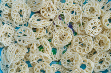 Full frame top view of raw, uncooked Indonesian crackers (Krupuk) in a textured, spiral, ring shape. Represents Asian snack food, abstract background, texture, and culinary pattern.