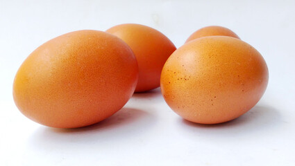 Four fresh brown chicken eggs placed on a white background.