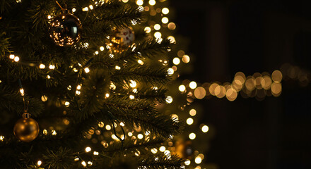 Close-up of a beautifully lit Christmas tree with golden ornaments, festive atmosphere