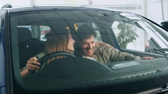 Inside a bright and modern auto salon, a couple shares laughter while exploring a new car. The atmosphere is lively as they engage in the excitement of the buying process.